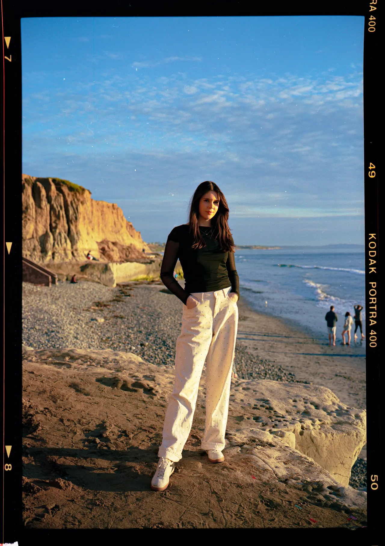 A figure on the sand below eroded sandstone bluffs in late afternoon light