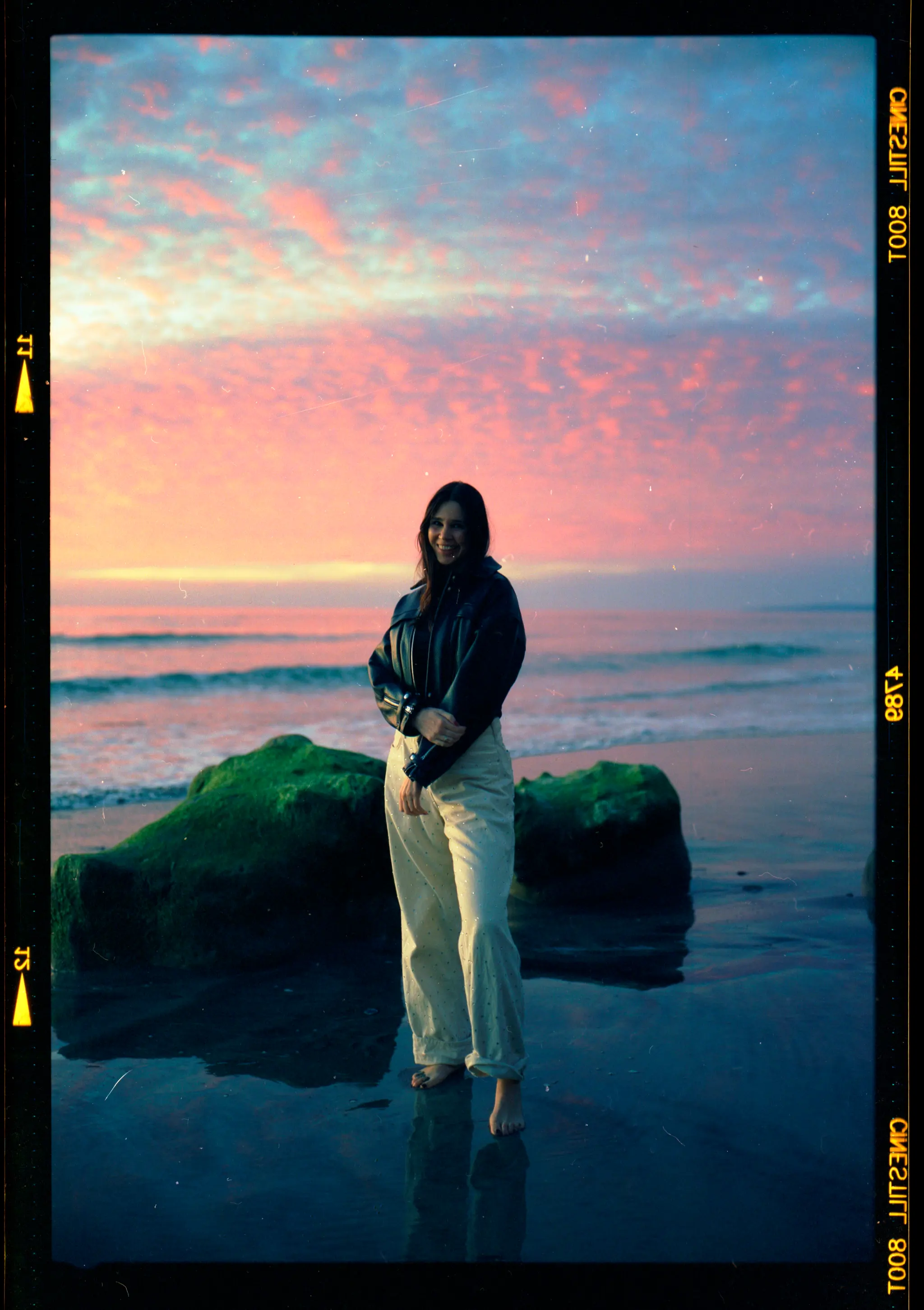 Pink and blue dusk sky over a figure standing on a coastal rock
