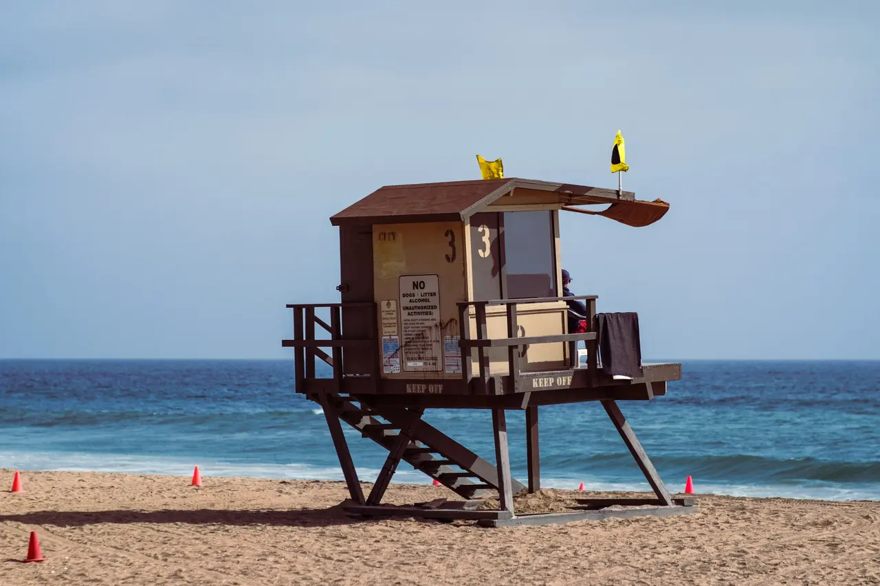 A numbered lifeguard tower on an empty beach with warning flags flying