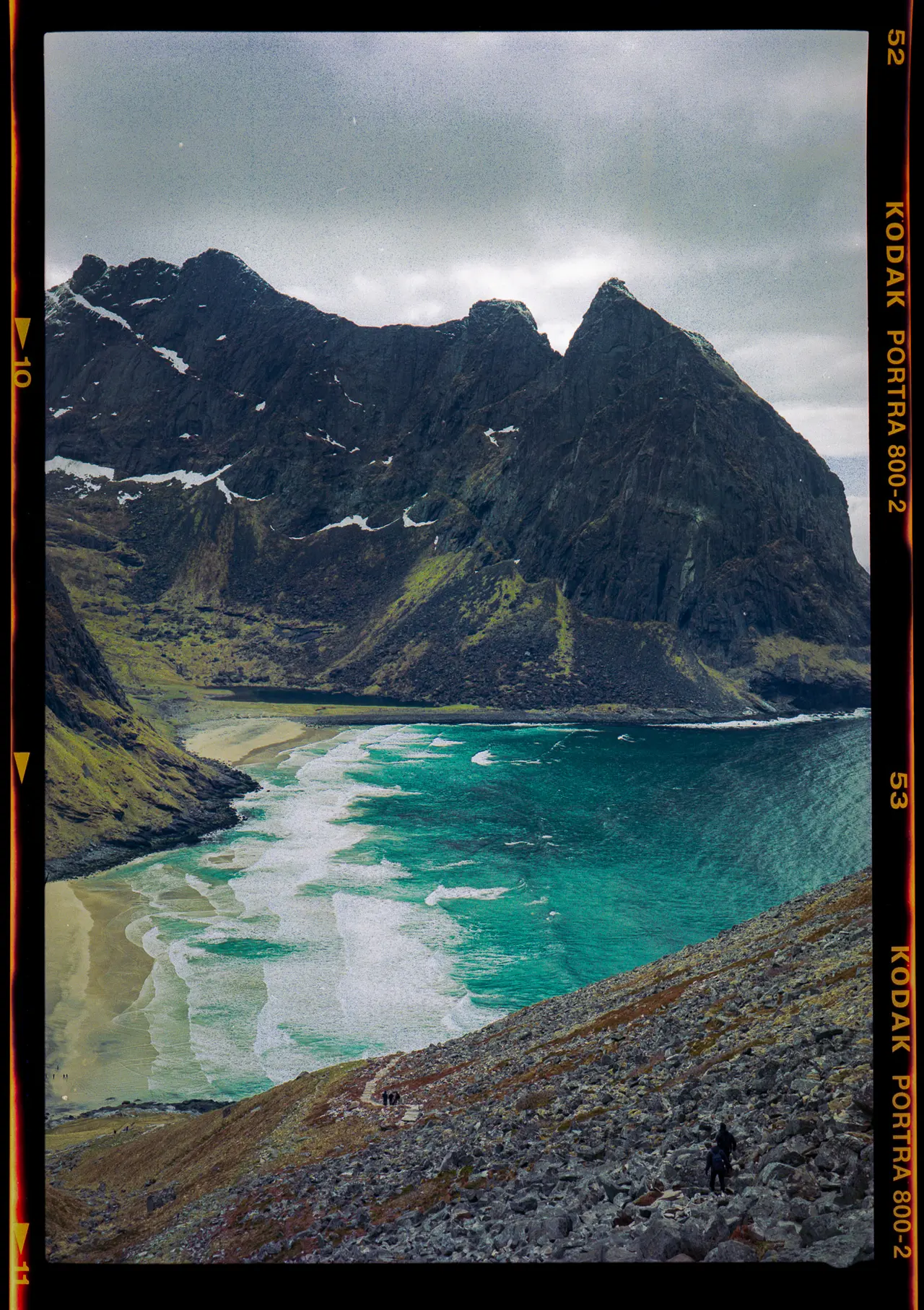 Turquoise water meeting a curved beach below steep Lofoten peaks